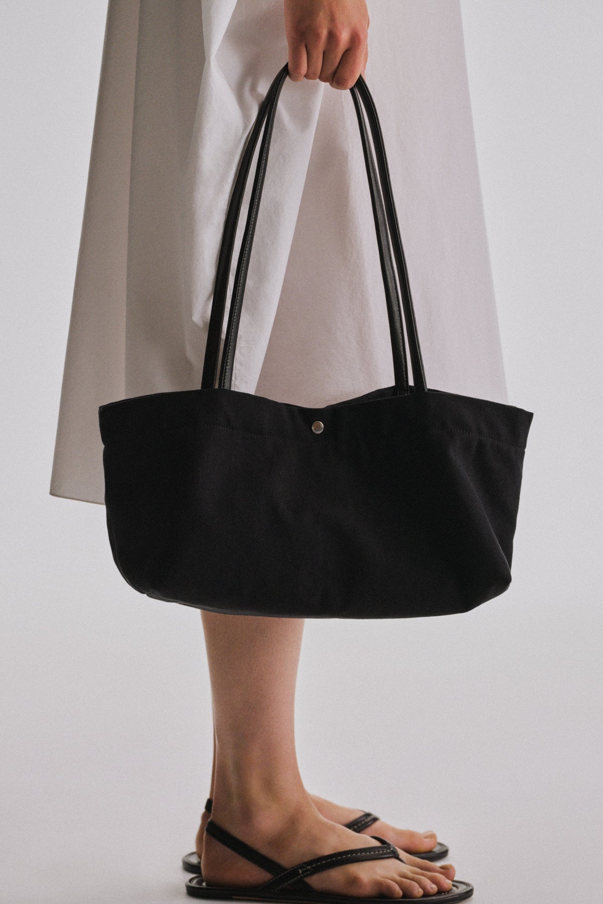 The Row Idaho Shoulder Bag in Black, carried by hand, worn close view — The Quiet Edition