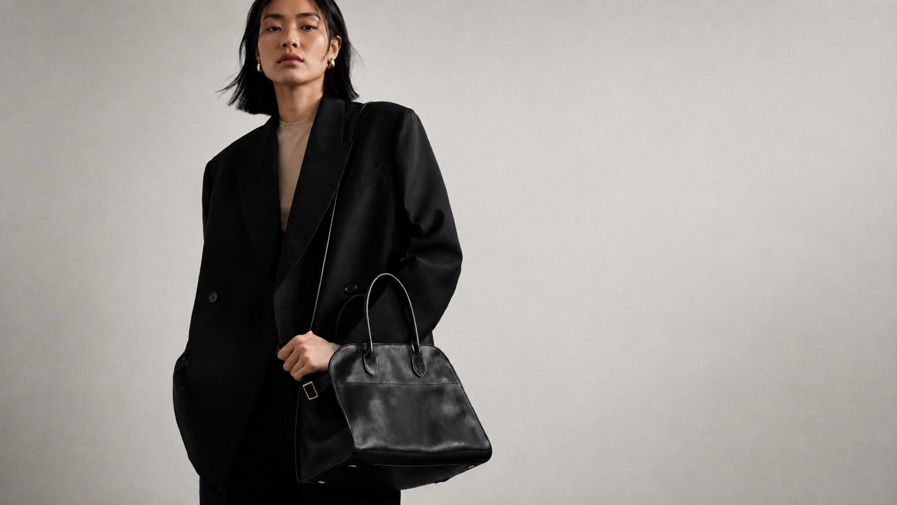 Model in a black blazer carrying The Row Margaux bag
