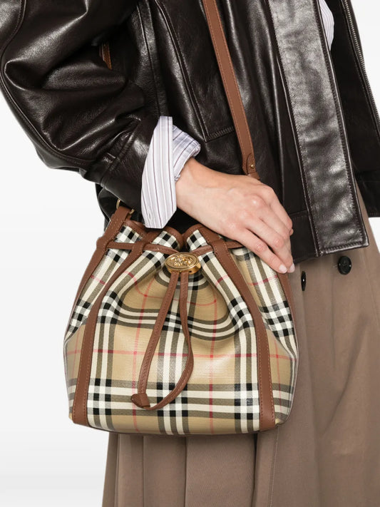 Burberry Small Check Bucket Bag worn crossbody with a brown leather jacket and taupe trousers