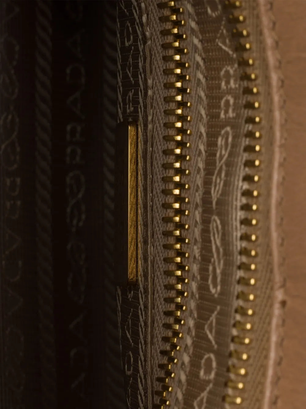 Prada Bonnie handbag interior detail showing logo-print nylon lining, gold zip and inside zip pocket