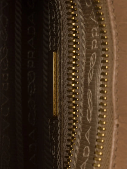 Prada Bonnie handbag interior detail showing logo-print nylon lining, gold zip and inside zip pocket