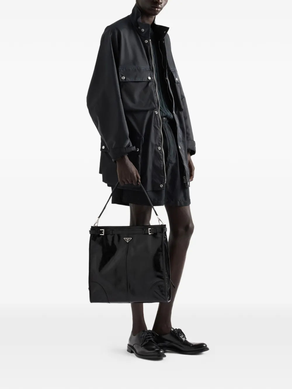 Prada Bonnie Leather Shoulder Bag in Black, carried by hand, worn view — The Quiet Edition