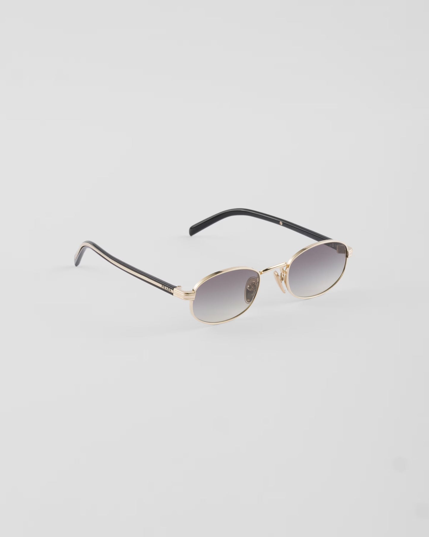 Prada PR B53 oval sunglasses in pale gold, three-quarter angle — The Quiet Edition