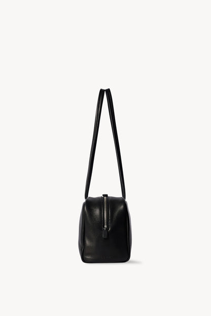 The Row Astra Bag in black, end profile showing the zip pull and full handle drop