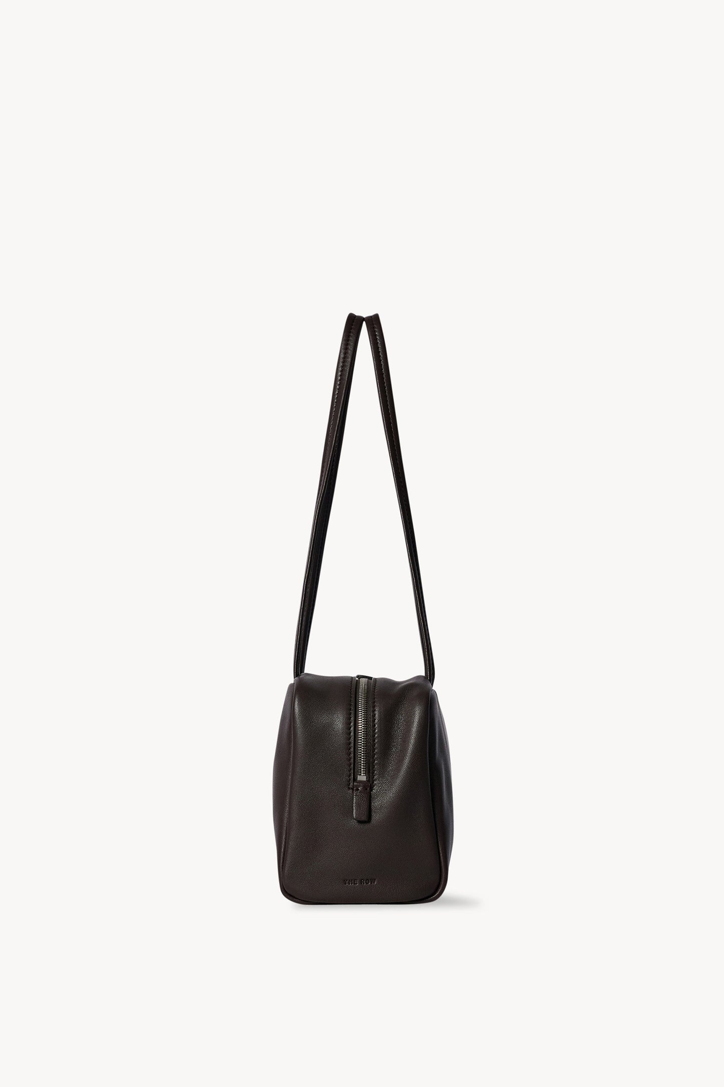 The Row Astra Bag in dark brown, end profile showing the zip pull and full handle drop