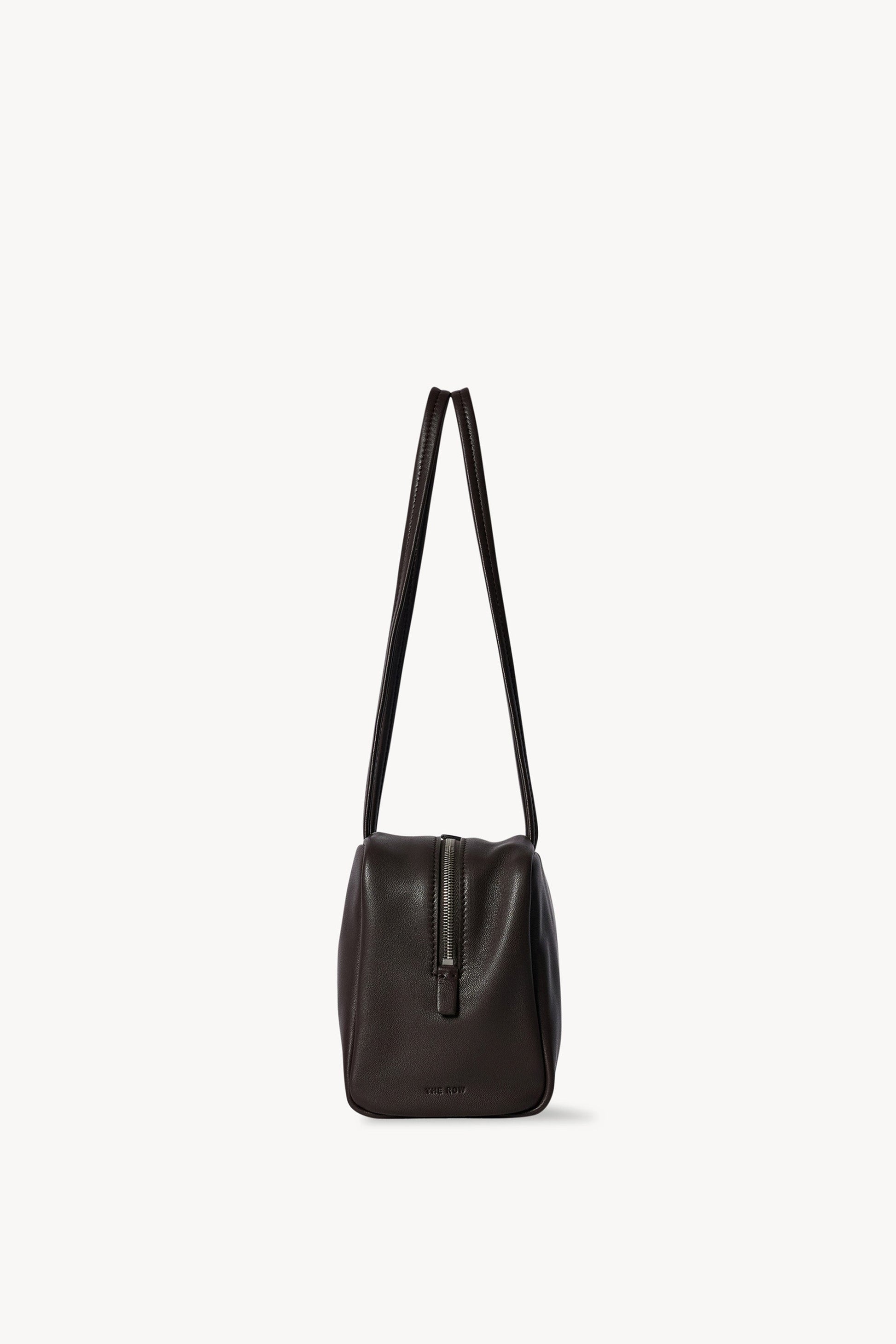 The Row Astra Bag in dark brown, end profile showing the zip pull and full handle drop