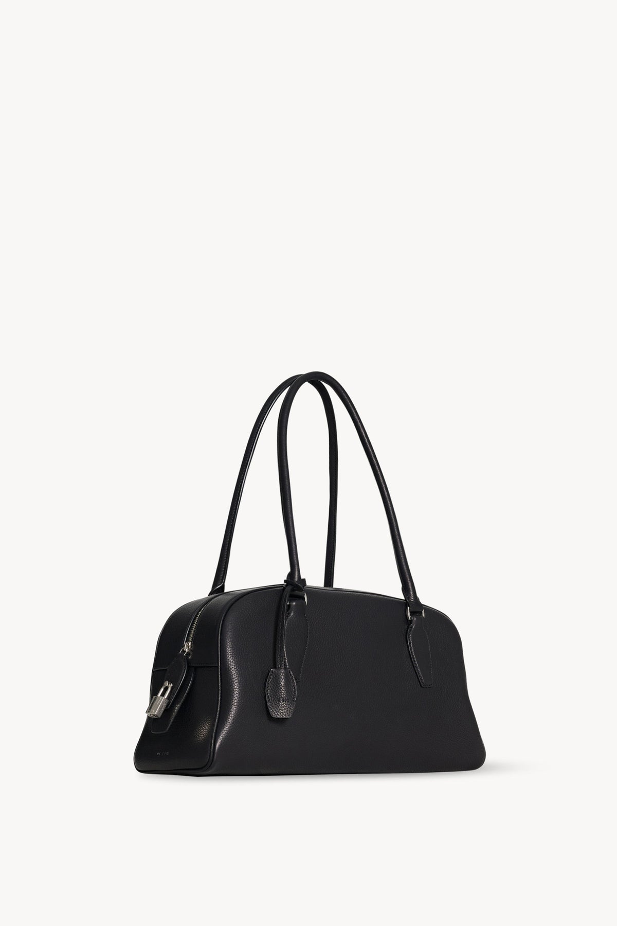 The Row E/W India Bag in black, three-quarter angle showing the top zip, padlock and leather key holder