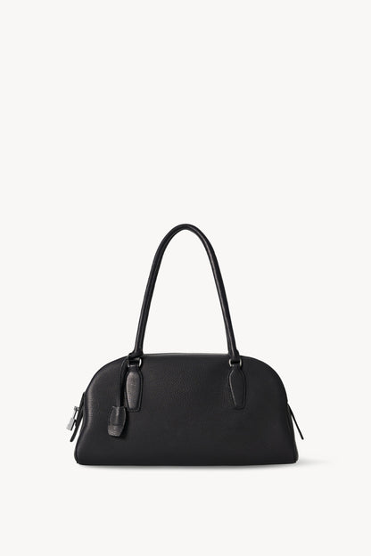 The Row E/W India Bag in black grained calfskin, front view with tubular handles and side padlock