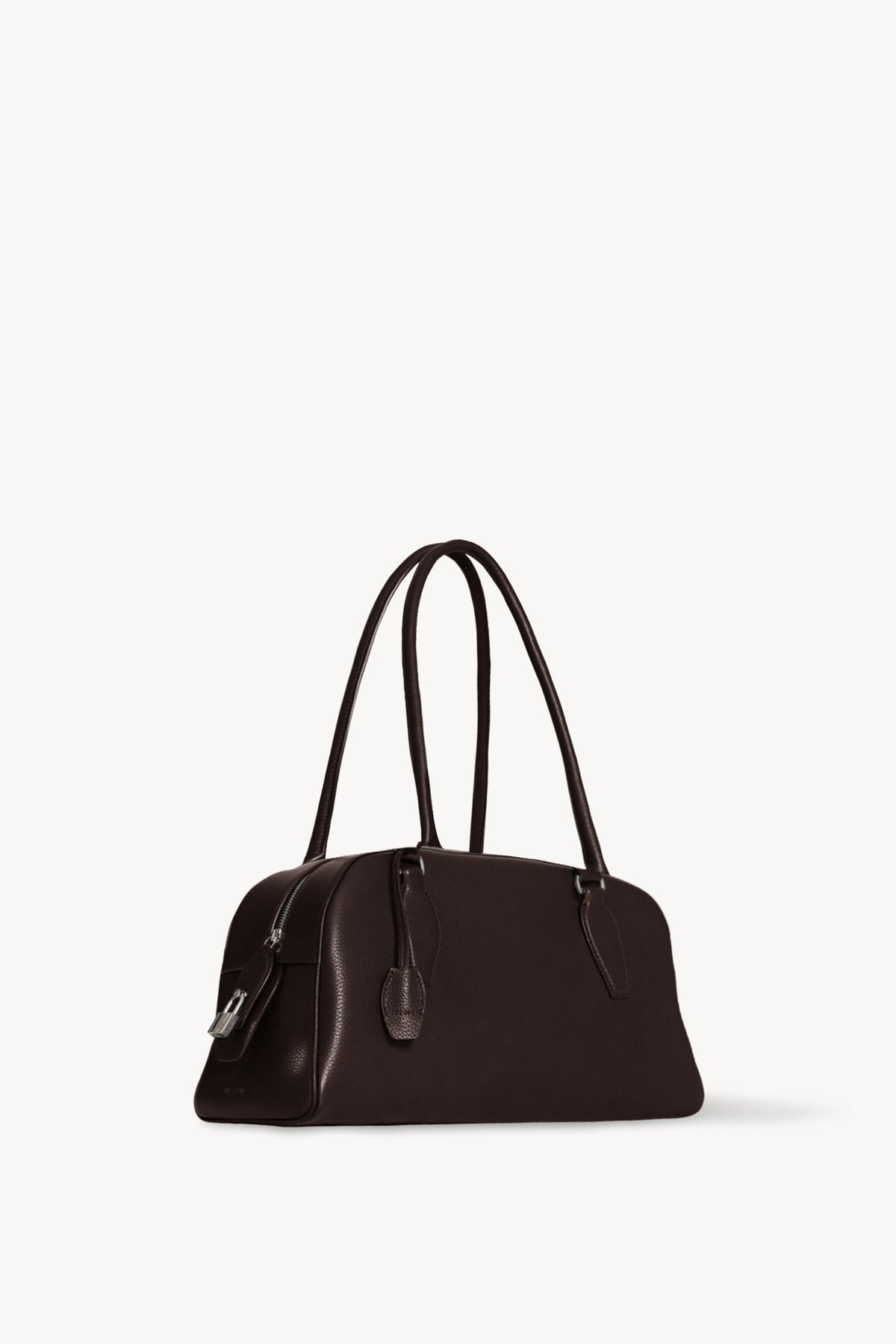 The Row E/W India Bag in dark brown, three-quarter angle showing the top zip and metal padlock
