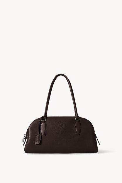 The Row E/W India Bag in dark brown grained calfskin, front view with extended tubular handles