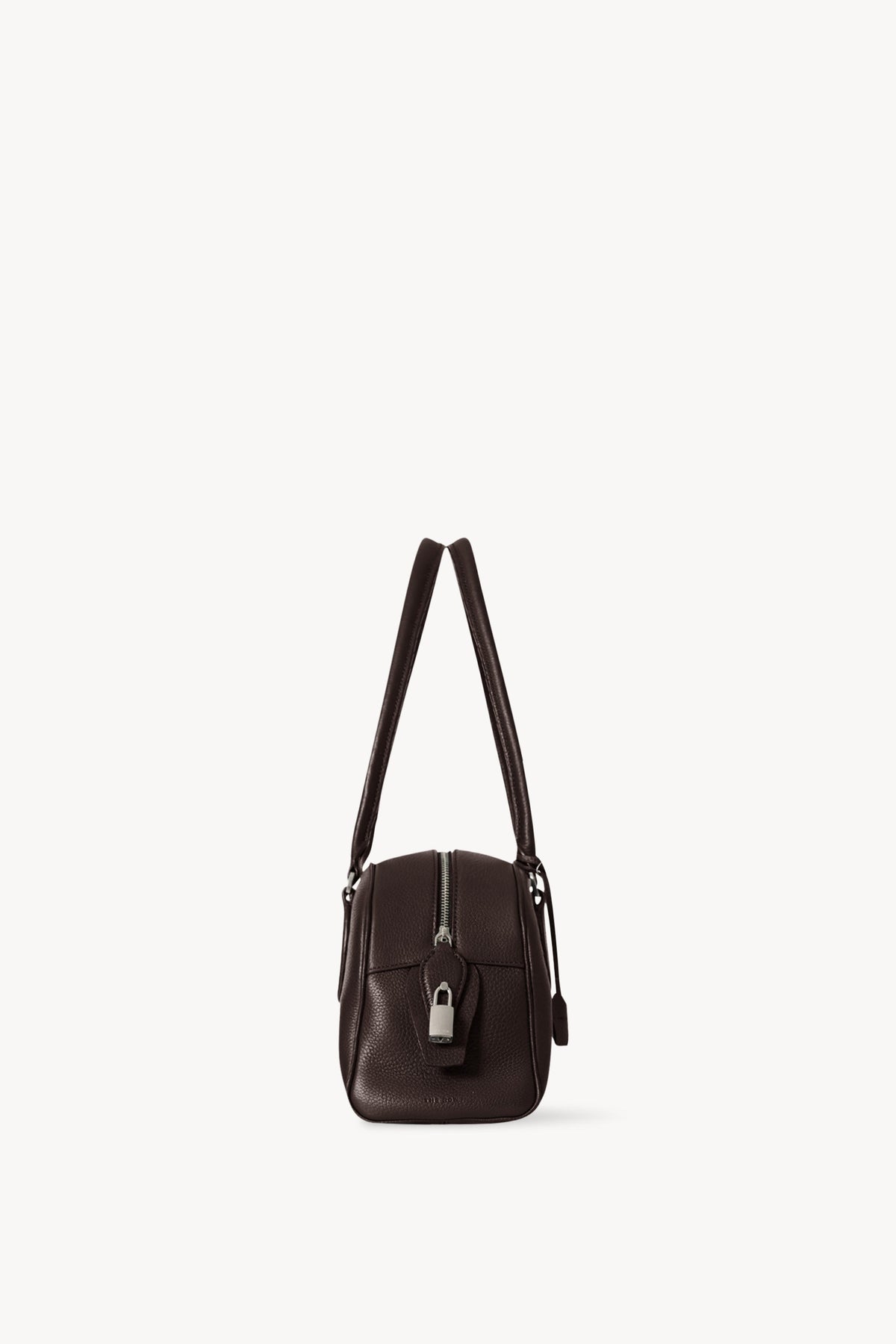 The Row E/W India Bag in dark brown, end-on side view with top zip and piped edges