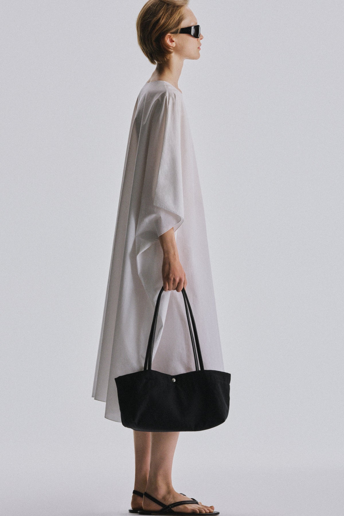 The Row Idaho Shoulder Bag in Black, carried by hand, worn full-length view — The Quiet Edition