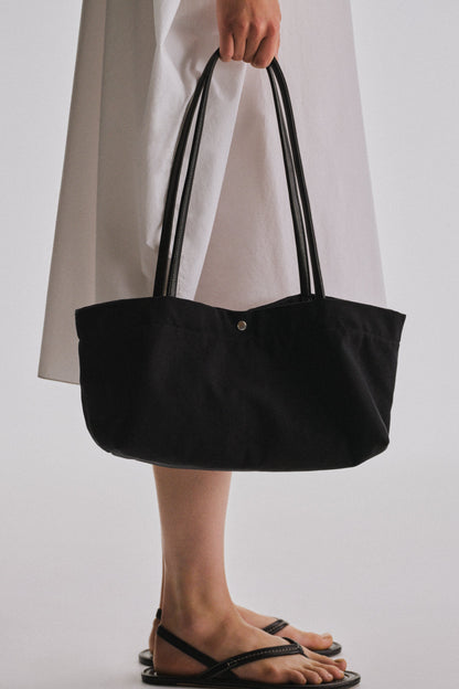 The Row Idaho Shoulder Bag in Black, carried by hand, worn close view — The Quiet Edition