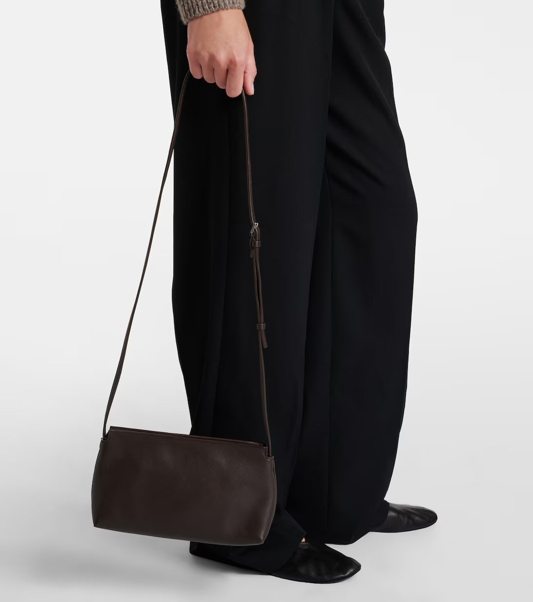 The Row Rene shoulder bag in brown, model holding by strap — The Quiet Edition