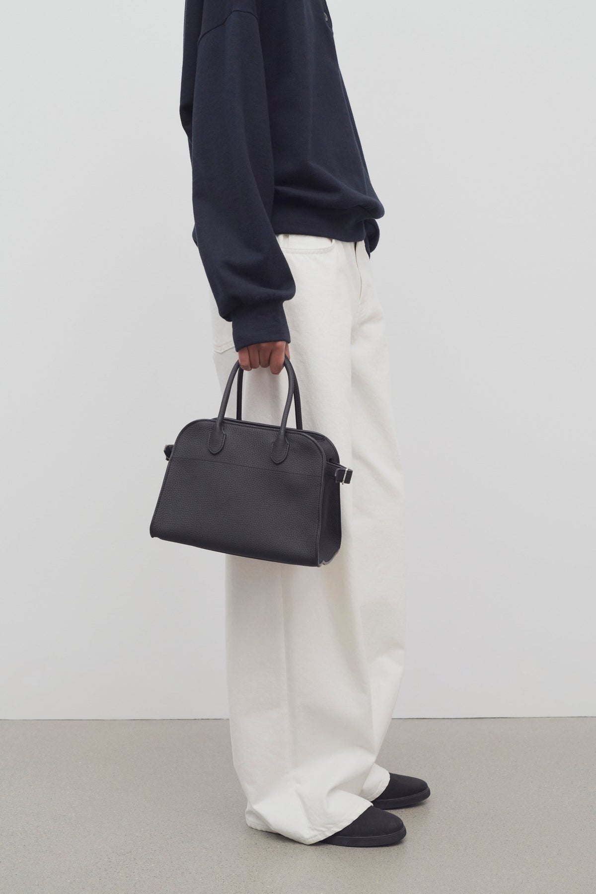The Row Soft Margaux 10 Bag in Black, carried by hand, worn view — The Quiet Edition
