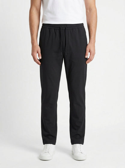 Zegna drawstring tapered trousers in black, model front — The Quiet Edition