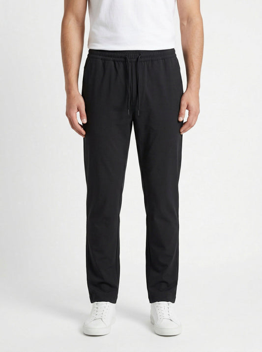 Zegna drawstring tapered trousers in black, model front — The Quiet Edition