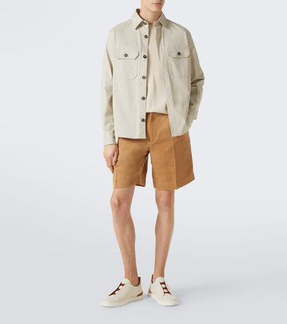 Zegna Triple Stitch leather sneakers in white worn by a model with tan shorts and cream overshirt